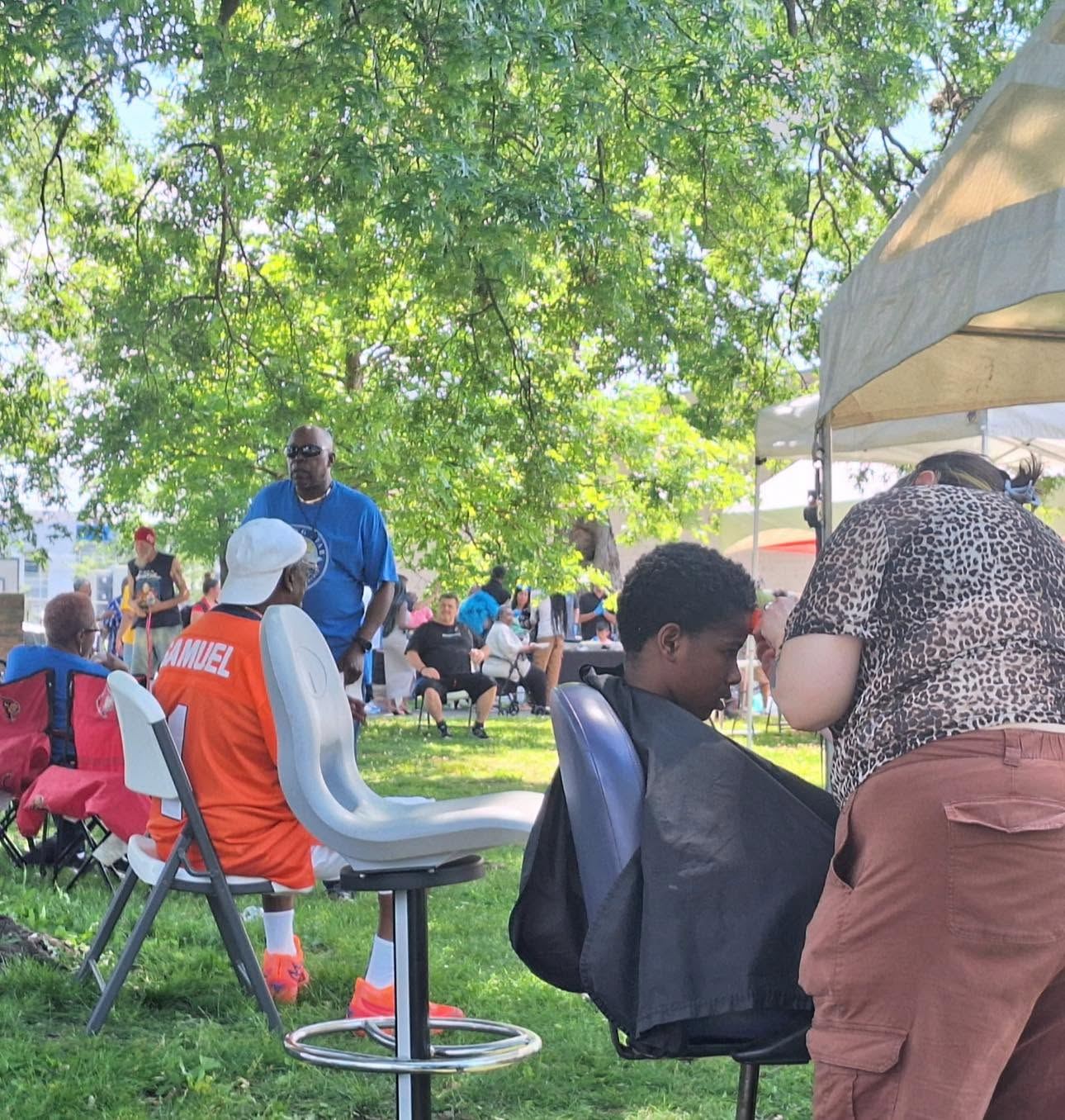 A barber giving a free haircut outdoors at a community day